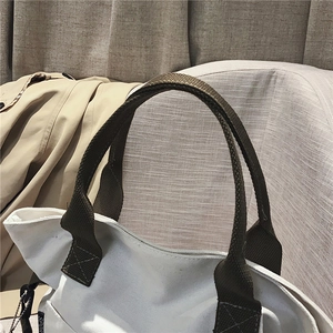 Detail of white canvas tote bag featuring high-density olive green woven handles and Sport label
