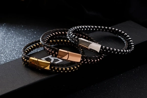 Detail of woven black leather bracelets with magnetic gold and silver steel clasps