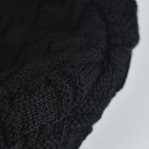 Detailed macro view of black chenille knit pattern texture with thick cable stitch