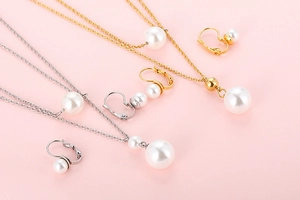 Detailed view of 18K gold and silver plated jewelry sets with pearls on pink background