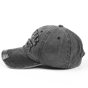 Detail einer verwaschenen Denim-Baseballcap mit BLACK-Stickerei und Lederaufnäher an der Seite