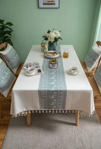 Detail of cream tablecloth with grey reindeer patterns and elegant tassel edge decor