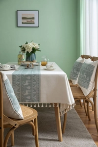 Detail of Nordic reindeer table runner with tassels and matching cushion covers on a wooden table