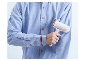 Pink lint roller being used on a blue shirt to effectively remove dust and fibers