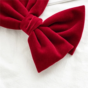 Close-up of a large red velvet bow hair clip showing soft fabric texture and knot detail