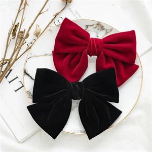 Detail of red and black velvet bow hair clips on white marble tray with magazine background