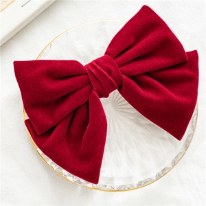 Close-up of a large burgundy velvet bow hair clip on a clear glass display plate