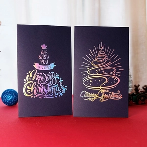 Golden and holographic Christmas cards with tree designs and envelopes on red base