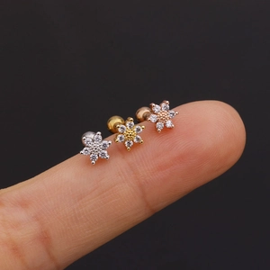 Macro shot of three tiny flower-shaped zircon stud earrings in silver, gold, and rose gold