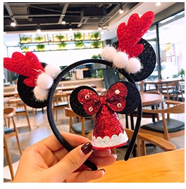 Detail of a Christmas headband with glittery red antlers and Santa hat held by hand