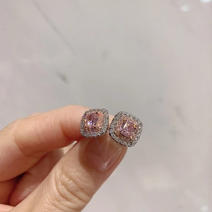 Detailed close-up of silver-tone stud earrings with square pink stone and double halo of zircon