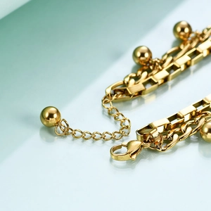 Detail of gold Cuban chain bracelet with lobster clasp and round ball charms