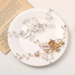 Detail view of handcrafted leaf hair clips with rhinestones and pearls on a white plate