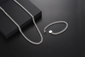 Close-up of titanium steel Cuban chain bracelet and necklace set on black background