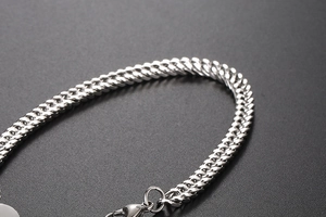 Close-up of a silver titanium steel Cuban chain bracelet with a secure lobster clasp