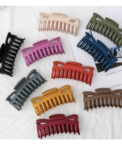 Variety of large matte hair claws in 10 assorted colors on a soft white fabric background
