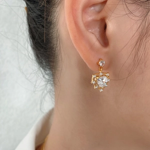 Close-up of heart-shaped gold stud earring with sparkling pavé zircons worn on ear