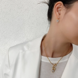 On-model view of a gold heart and bow necklace set with cubic zirconia detailing