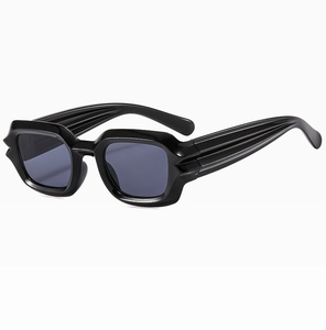 Close-up of black punk sunglasses featuring wavy textured frames and thick striped temples