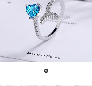 Macro shot of silver ring featuring a blue heart gemstone and diamond-set fishtail detail