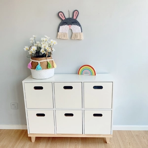 Bohemian woven tassel basket decoration on a minimalist white wooden dresser in a nursery