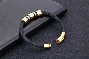 Macro view of men's black braided leather bracelet with gold magnetic buckle on leather