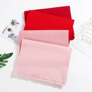 Detail of soft fringe texture on stacked cashmere-style scarves in gradient pink tones