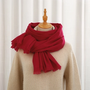 Close-up of bright red cashmere-feel winter scarf with soft fringes on a beige sweater