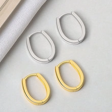 Detail view showing pair of oval hoop earrings in polished gold and silver finishes