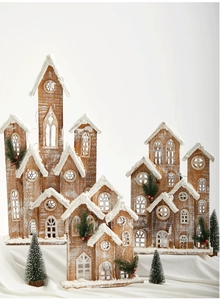 Detailed view of lit wooden Christmas house ornaments with faux snow and pine accents