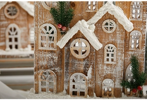 Detail of wooden Christmas house with artificial snow and festive greenery accents
