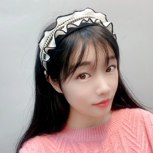 Detail of knitted ruffle headband with pearls on a model showing black and white texture