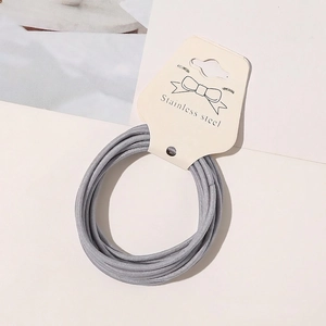 Close-up of grey elastic hair ties with woven texture on a cream paper display card