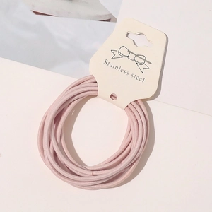 Detail of light pink elastic hair ties on a white card display with bow illustration