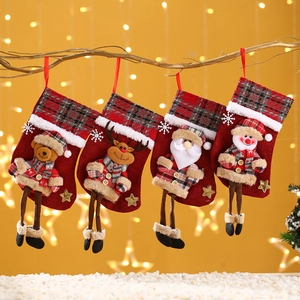 Detailansicht vier weihnachtlicher Socken mit Plüschfiguren an einem Ast hängend