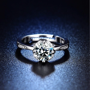 Detail shot of a six-prong silver ring with a large moissanite center stone and side diamonds