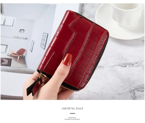 Detail shot of a dark red crocodile pattern wallet with a gold zipper held in hand