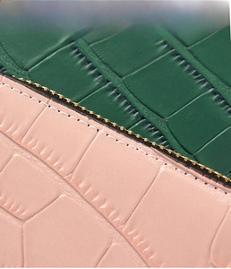 Detail of pink and green crocodile embossed leather with zip and fine stitching