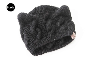 Detail of black knit cat ear beanie featuring cable knit texture and small leather tag