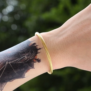 Macro view of gold twisted rope texture on stainless steel bangle in natural light
