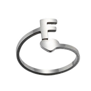 Detail of silver letter F open ring with a small heart and brushed metal texture