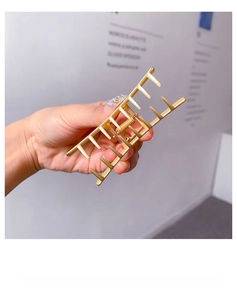 Close-up of a matte gold metal hair claw clip with a sleek long comb tooth design