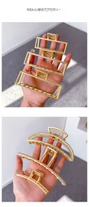 Detail view of large matte gold metal claw clip with rectangular hollow structure