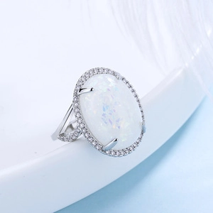 Macro shot of silver ring featuring white oval opal surrounded by micro-pave crystals