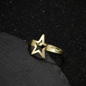 Minimalist gold hollow star ring for women placed on a black textured rock surface