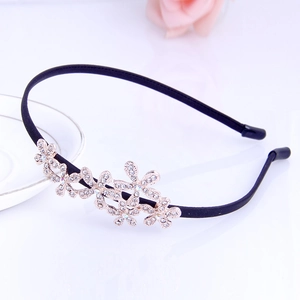 Macro shot of black rhinestone headband with gold metal flower and clear crystal detail