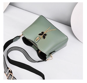 Detail of green shell bag with butterfly pendant and stylish woven wide shoulder strap