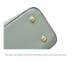 Close-up of sage green leather bag bottom featuring gold studs and white stitching