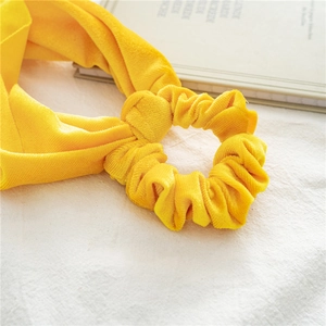 Macro detail of yellow velvet scrunchie with bow tie knot showing soft fabric texture