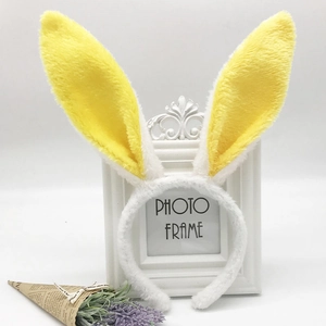 Detail of white plush rabbit ears headband with yellow sequin accents on white background